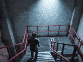 a man is walking up a set of stairs with a red railing