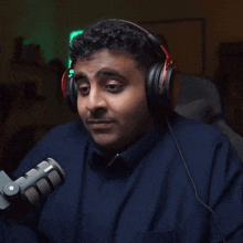 a man wearing headphones stands in front of a rode brand microphone