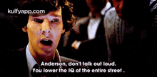 a man in a suit and tie is talking to another man in a dark room .