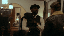 a man in a hat is talking to another man in a suit