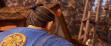 a man with a ponytail and a blue shirt with a yellow flower on the back
