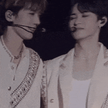 a couple of men are standing next to each other on a stage with their eyes closed .