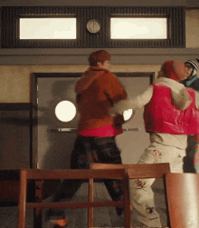 two people are fighting in front of a clock on the wall .