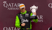 a man holding a trophy in front of a qatar advertisement
