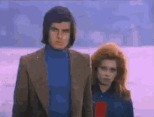 a man and a woman standing next to each other in front of a snowy field