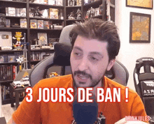 a man with a beard is sitting in front of a microphone and says 3 jours de ban