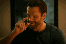 a man with a beard is smiling and holding his finger to his face