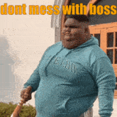 a fat man wearing a blue cape cod hoodie holds a bat