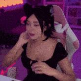 a woman wearing a cat ear headband sits in a pink and white chair