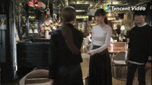 a man and two women are standing in a restaurant with a tencent video logo in the background