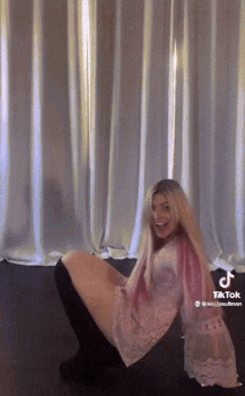 a woman in a pink dress is kneeling down in front of a white curtain with a tiktok watermark