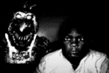 a black and white photo of a man standing next to a statue of a dinosaur .