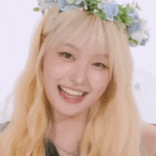 a woman with blonde hair and a flower crown on her head is smiling and giving a thumbs up .