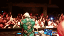 a man in a green floral shirt is playing music in front of a crowd of people
