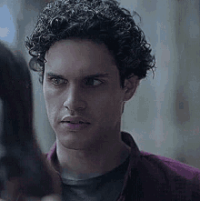 a young man with curly hair is looking at a woman .