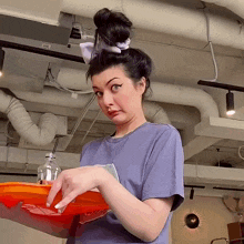 a woman with a bun on her head is holding a tray with a sticker that says ' a ' on it