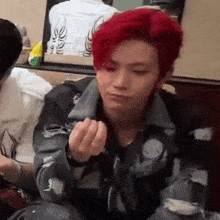 a young man with red hair is sitting at a table in a restaurant eating food .