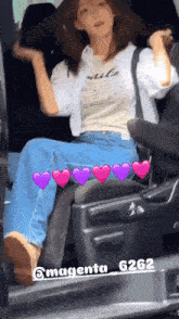 a woman is sitting in the back seat of a car with purple hearts on the seat