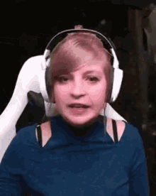a woman wearing headphones and a blue shirt is making a face .