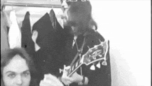 a man with long hair is playing a guitar in a black and white photo .