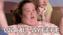 a very fat woman is laying on a bed with the words `` was it ayeeee '' written on the screen .