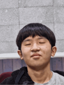 a young man with his eyes closed is wearing a black jacket