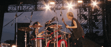 a man playing a guitar on a stage with a drum set