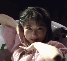 a woman in a pink shirt is sitting in a bathtub with her hands on her face