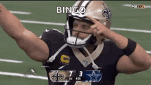 a football player is wearing a helmet and making a funny face on the field .