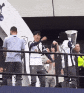 a group of people standing in front of a fence holding a trophy