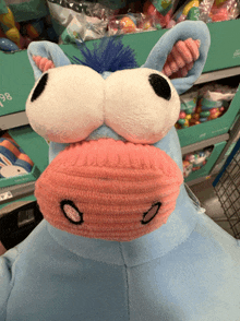 a stuffed animal with big eyes and a pink nose is on display in a store