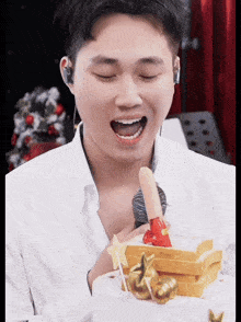 a man in a white shirt is eating a cake made out of slices of bread