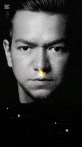 a black and white photo of a man 's face with a sparkler coming out of his mouth