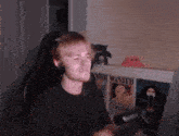 a man wearing headphones is sitting in front of a computer and a wanted poster .