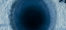 a person is standing in the snow near a hole in the ground .