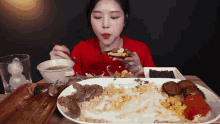 a woman in a red shirt is eating a plate of food with a fork