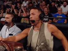 a man wearing a headset holds a championship belt