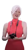 a woman in a red dress holding a camera and smiling