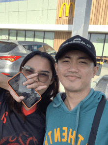 a man and a woman are posing for a picture in front of a mcdonald 's restaurant