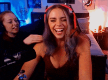 a woman wearing headphones is laughing while another woman petting her