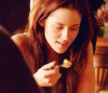 a woman eating a piece of food with a spoon
