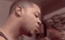 a close up of a man 's face with his eyes closed and a woman behind him .
