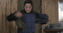 a woman is standing in front of a bamboo wall wearing a black jacket