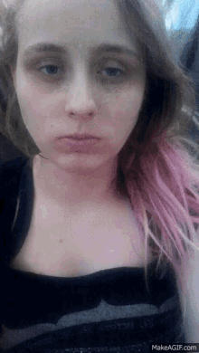 a woman with pink hair is taking a selfie