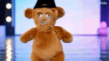 a teddy bear is wearing a black hat and dancing on a stage .