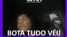 a woman is talking into a microphone with the words bota tudo vei written below her