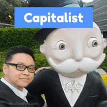 a man standing next to a statue of monopoly man with the word capitalist above it