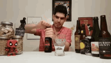 a man is pouring beer into a glass with a bottle of bourbon county on the table behind him