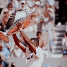a man holds up a trophy that says champions league