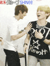 a man wearing a t-shirt that says shinee stands next to another man